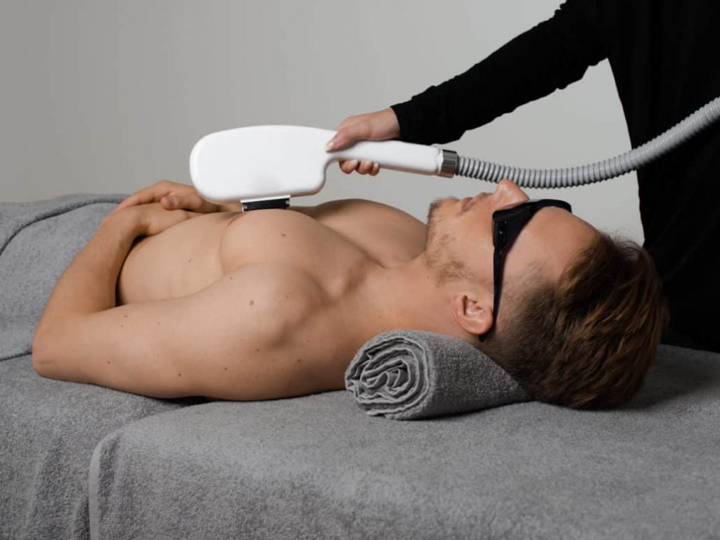 Esthéticienne en train de faire une épilation définitive au laser sur le torse d’un client